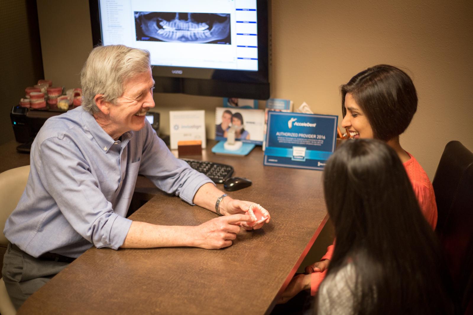 Doctor reviewing dental health with mom and daughter